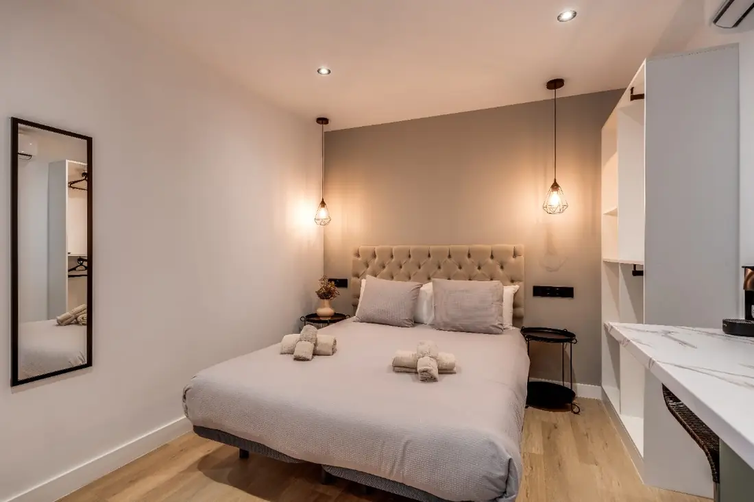 The Micro Suite from the door: the bed, a full-length mirror and white shelving over a marble worktop