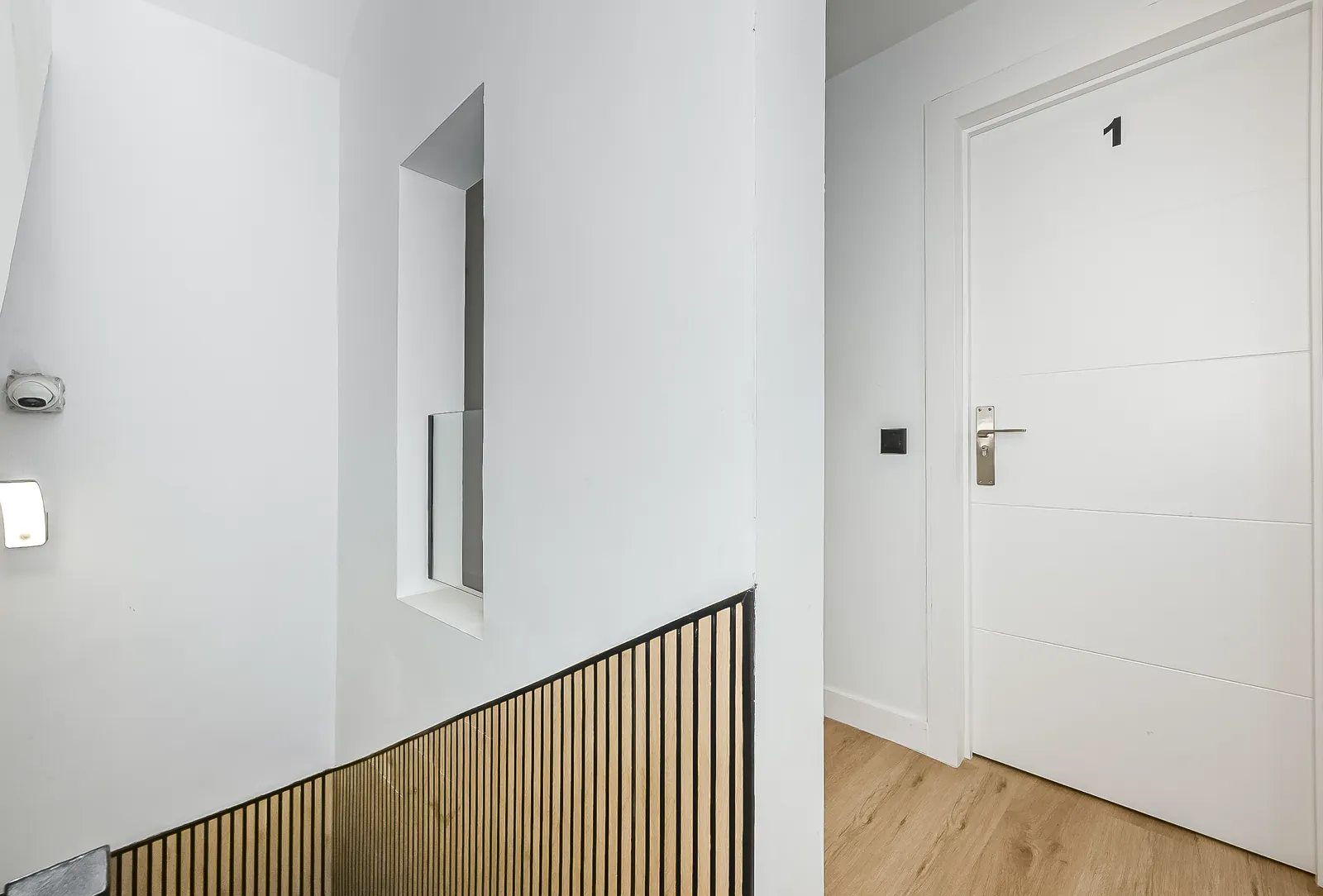The landing outside Room 1: oak slats along the stairs and the door marked 1