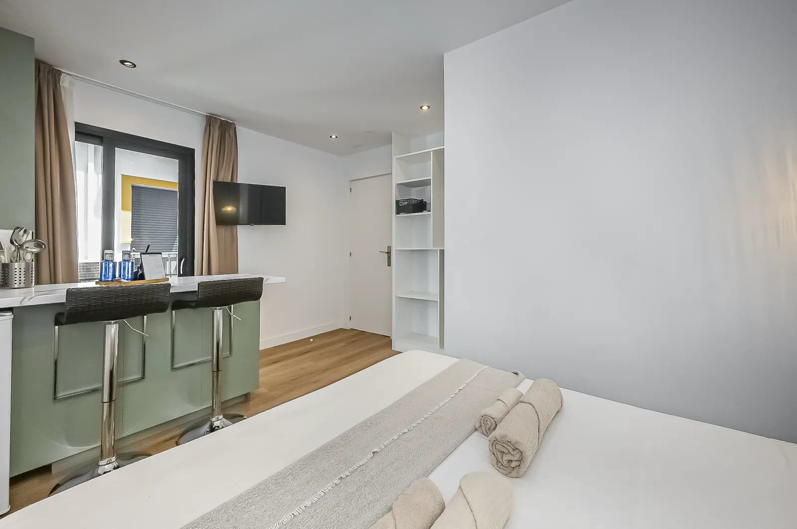 Room 1 from the bed: the breakfast bar with two stools, the television and the window onto the lane