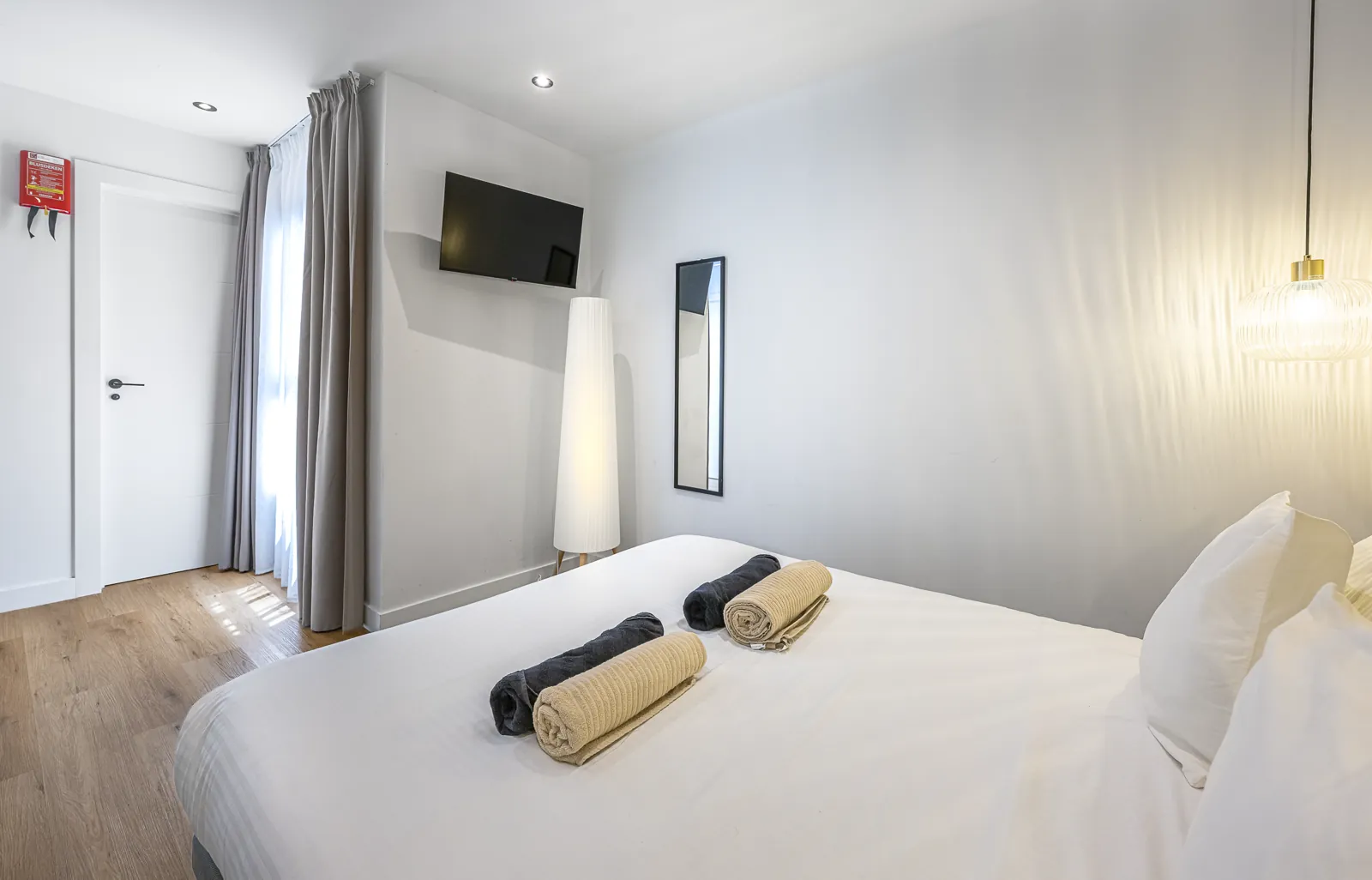 The Signature Suite from the bed: the television, a floor lamp and the curtained window