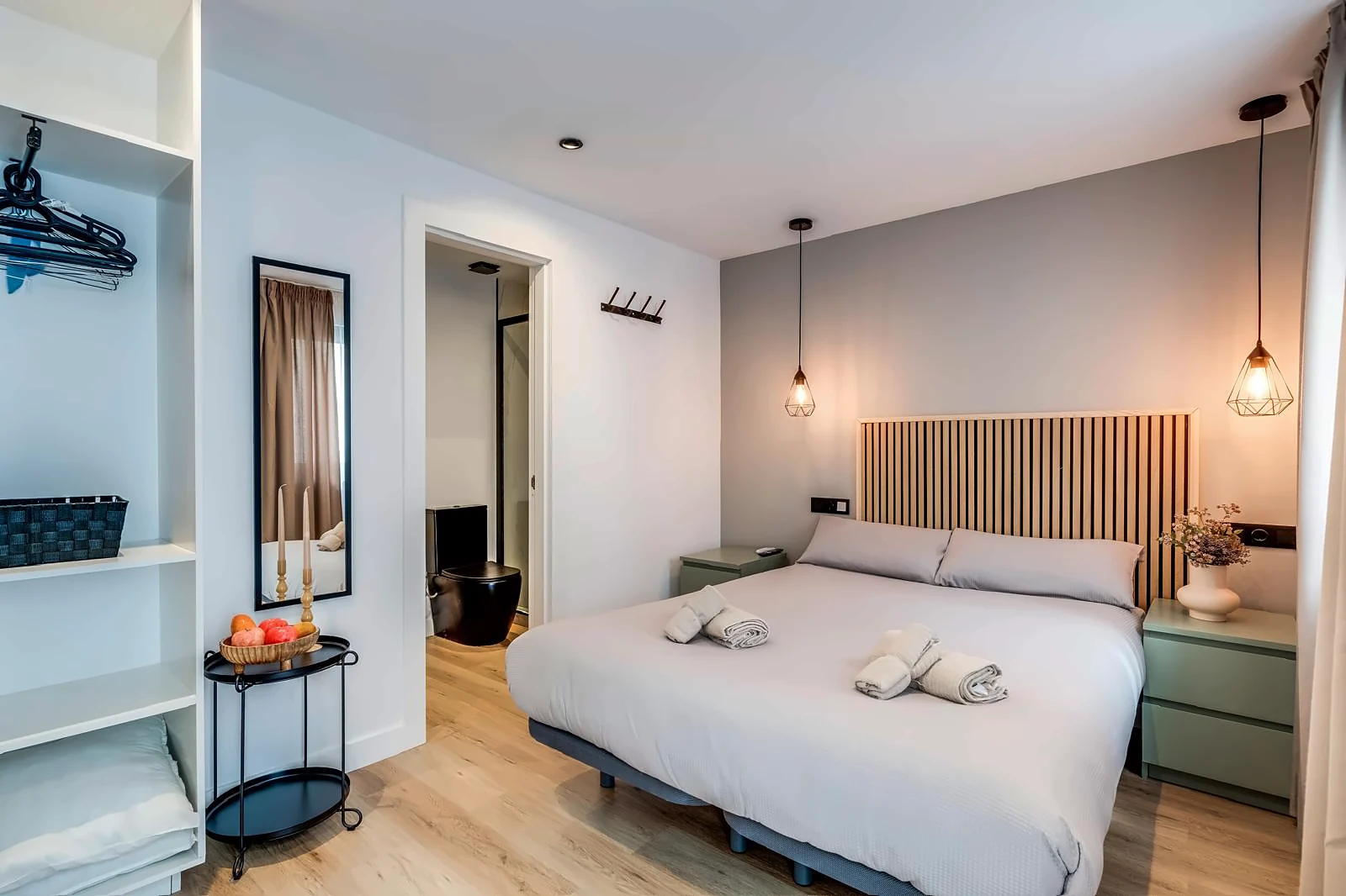 The Micro Suite: a double bed against an oak slat headboard under two wire pendants