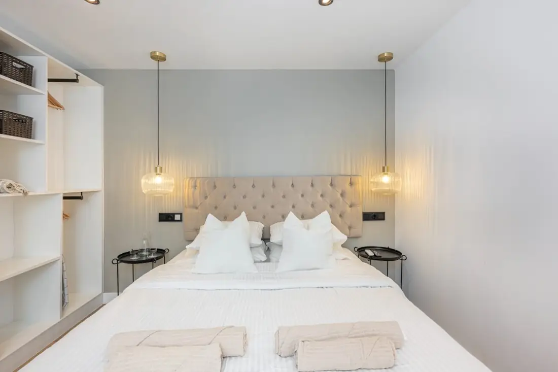 The bed centred between two white shelving units, with a pendant light on either side